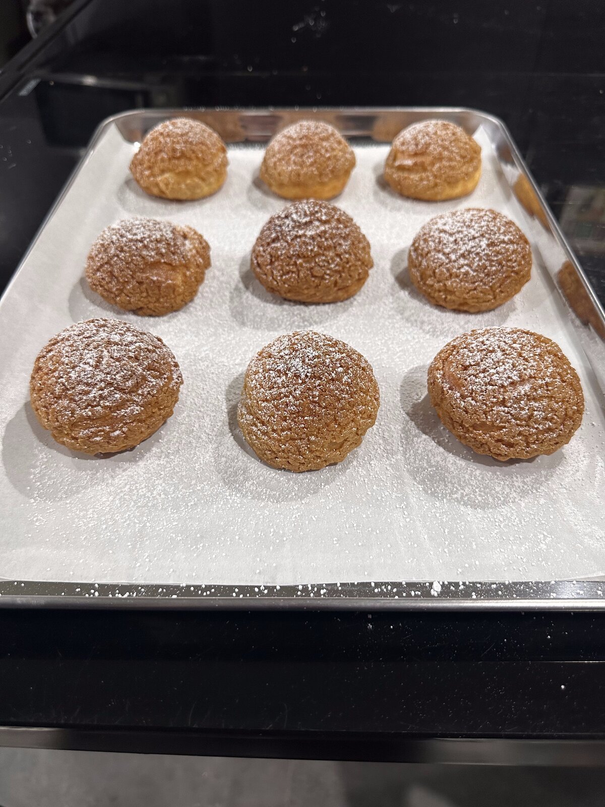 Freshly baked choux pastries on a tray